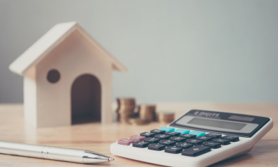 A calculator on a desk next to a model house