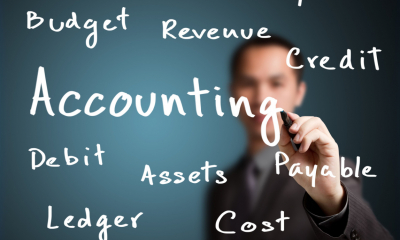 A man is writing key accounting terms on a board