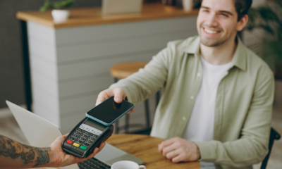 A young man uses his smartphone to make a digital payment