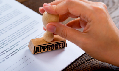 Close-up of a hand stamping a loan application with the word approved