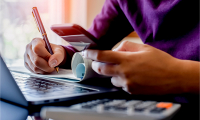 Banking via a smartphone app with a blank cheque book and calculator ready on a desk