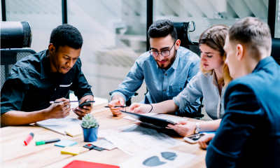 Four employees sit at a table and share opinions about a project they are collaborating on