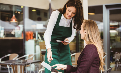Business woman being served by a waitress in a cafe