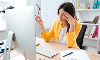 Businesswoman having head pain in office wring a bright orange jacket