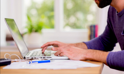 Man in blue top working from home using a laptop