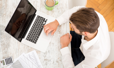 Man in white shirt using a laptop to do a business tax plan