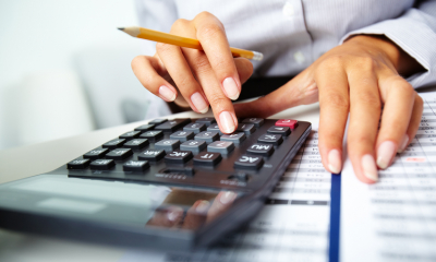 Woman in a striped shirt holding calculating corporation tax over different dates