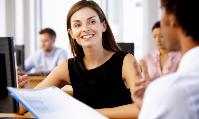 Smiling woman in a black top discussing employee insurance with an employee
