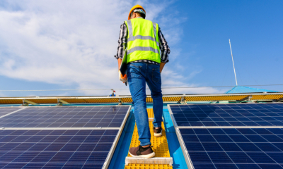 A workman fits solar panels on a roof