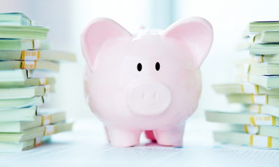 Piggy bank stood between piles of money
