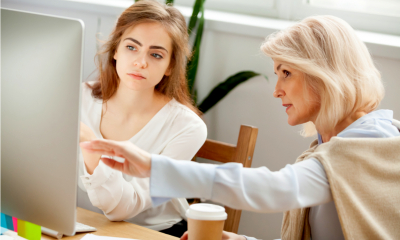 An SME owner shows her employee how to do something on the computer