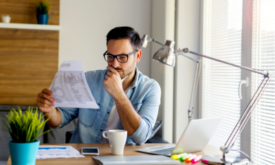 Man in glasses looking at a piece of paper with various sets of data on them