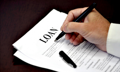 Male director signing a loan with a black pen on a wooden table