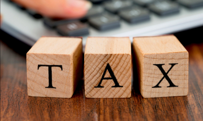 Three coloured cubes spelling out TAX on a table