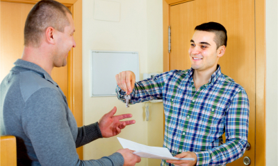 A landlord hands over a key and rental contract
