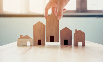 Hand choosing wooden house model, landlord tax concept
