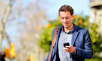 A man browses the internet on his smartphone while walking to work