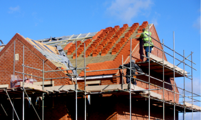 A worker from a building firm standing on scaffolding outside a house