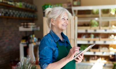 Old entrepreneur assistant with digital tablet in small grocery store