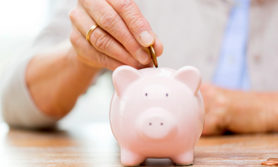 Pensions Close up of female hand putting coins into a ceramic piggy bank