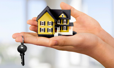 Person holding a small toy building in their hands with a key dangling from their finger