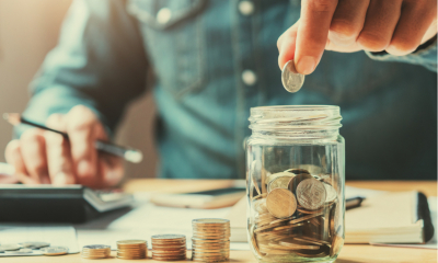 A man counts coins into a jar representing National Insurance contributions