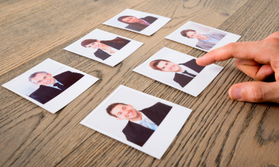 Table with photos of accountants. A hand points at one of the photos.