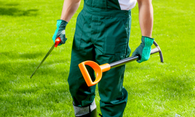 Gardener with his tools walking across a green lawn