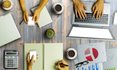 Management working together on a busy desk, overhead shot