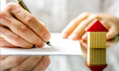 A hand signs a contract agreeing to release the equity in a home