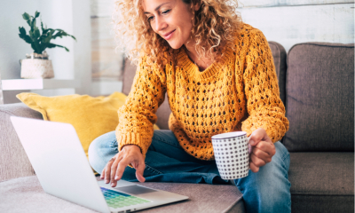 Lady with blonde curly hair working on her notebook on the sofa at home