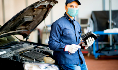 Masked car mechanic holding a jug of motor oil during coronavirus pandemic