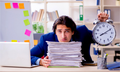 A business owner sits behind a big stack of financial documents, worrying about the tax return deadline.