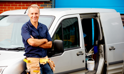 Tax A self-employed man stands next to his work van