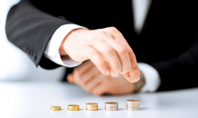 Your money and your business Arm in suit sleeve sorting piles of coins